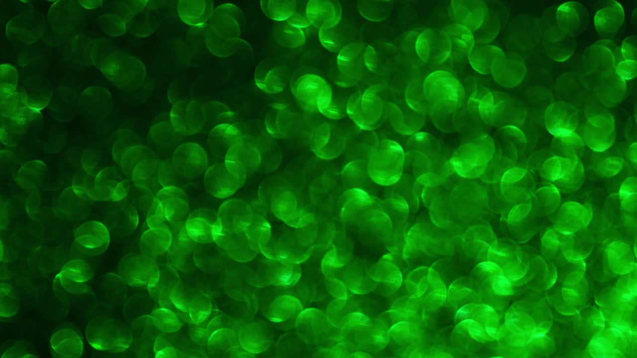 fondo de video 4k de brillo brillante abstracto. fondo de brillo verde con textura brillante. luz esmeralda brillante, chispas de lentejas y fondo de aluminio brillante.