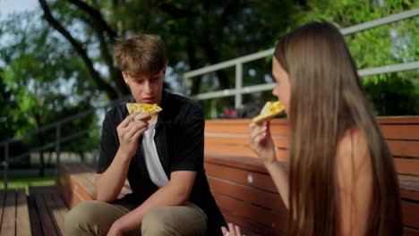 young couple enjoying a pizza together in the park