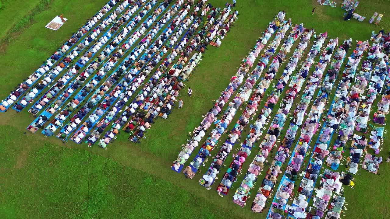 Suuri joukko muslimeja kumartumassa rukoukseen Eid al-Fitr -juhlan aikana, ilmakuva luonnonympäristössä.