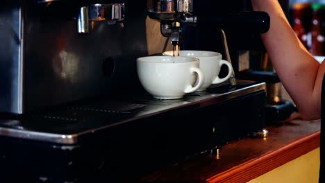 Waitress-making-cup-of-coffee-at-counter-in-kitchen