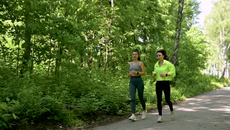 two happy and smiling sportswomen running in the park