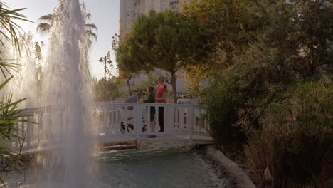 Mother-with-children-walking-in-hotel-garden-with-fountains