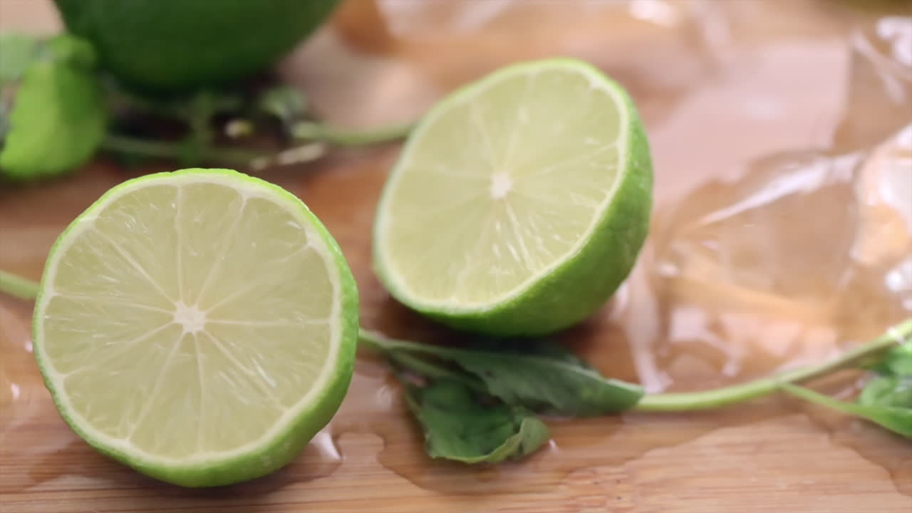 Close up of cut up lime with ice and mint on a wooden cutting board