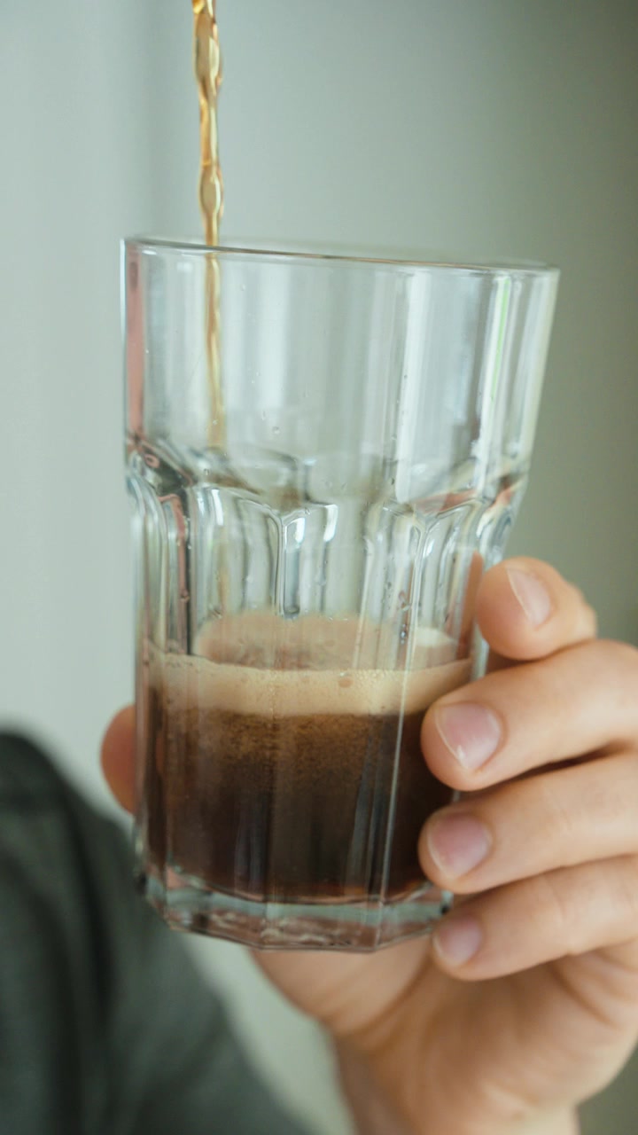 Primo piano di cola versata in un bicchiere, che simboleggia bevande zuccherate, consumo eccessivo di zucchero, stile di vita non salutare, rischio di diabete e consapevolezza nutrizionale.