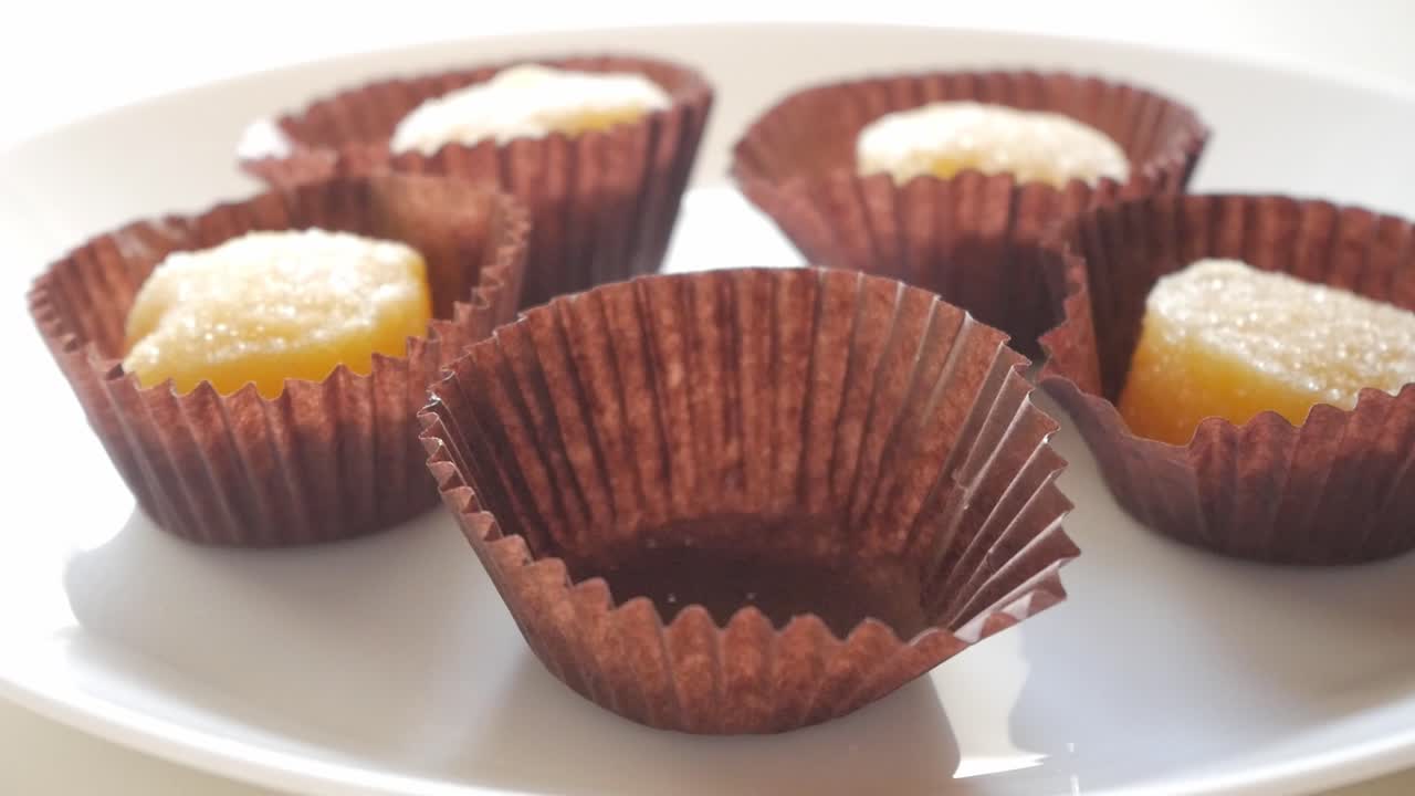 Traditional Spanish sweet egg yolks placed in brown paper cups on a white plate
