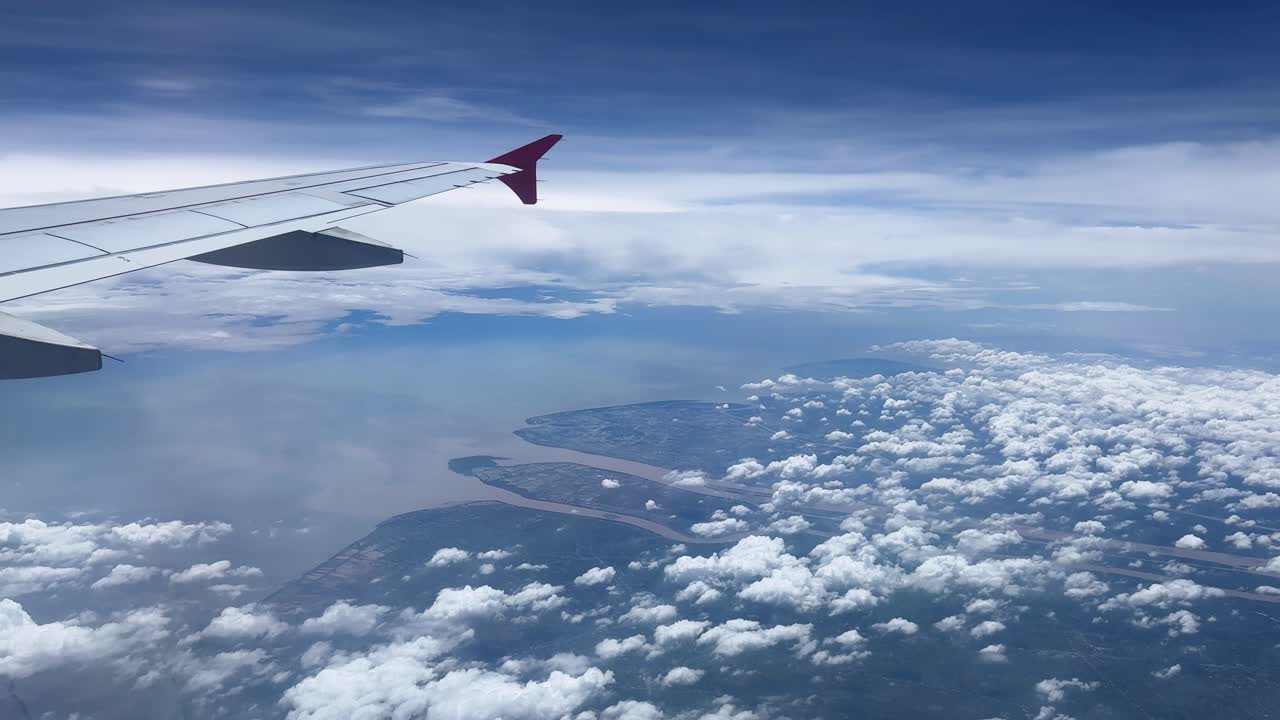 Vingeudsigt fra fly, blå himmel, skyer over havet, rejse