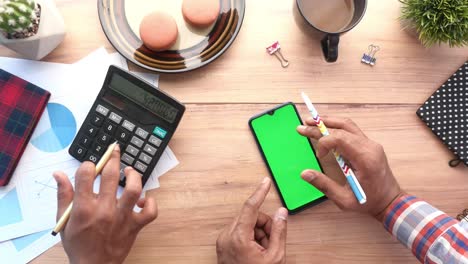persona que trabaja en un escritorio con un teléfono inteligente y una calculadora