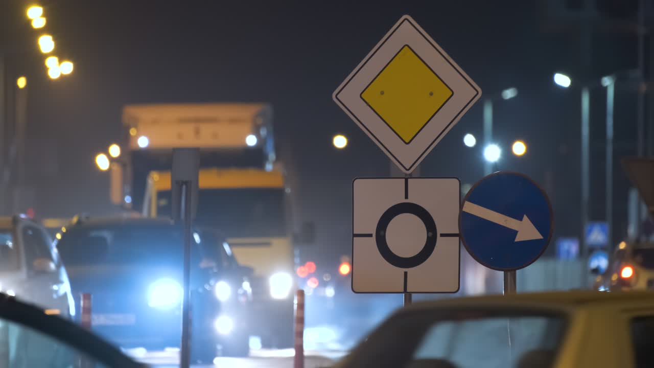 señales de carretera de rotonda con coches borrosos en el tráfico callejero de la ciudad por la noche. concepto de transporte urbano