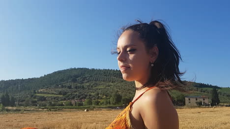 young brunette girl singing in a wheat field at the beginning of summer