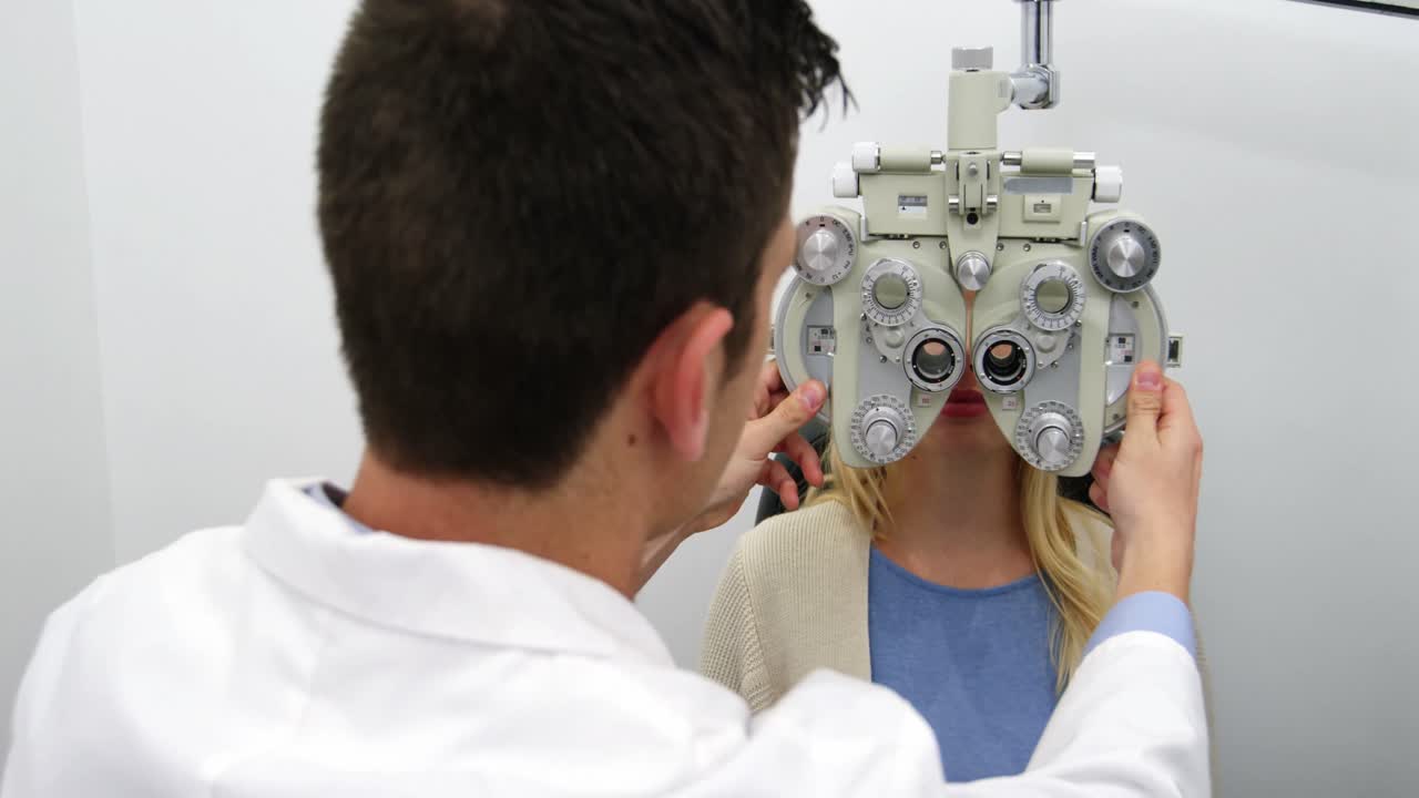 optometrista sorridente che esamina una paziente su un phoropter