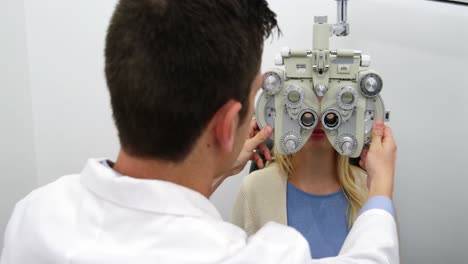 optometrista sonriente examinando a una paciente femenina en el phoropter