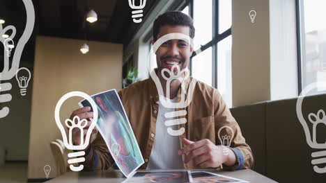 animation of lightbulb icons over biracial businessman holding photo