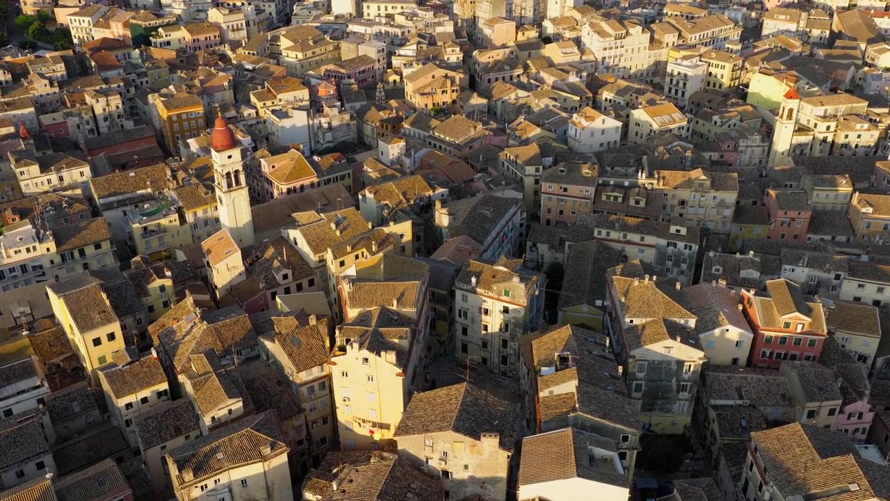 Vista drone di edifici tradizionali nella città vecchia di Corfù all'alba, in vicoli stretti e tortuosi con case color pastello, caffè e negozi, con la chiesa di San Spiridione in vista.