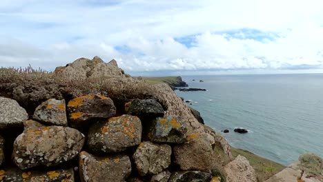 a rustic cornish stone wall with the ocean in the back ground