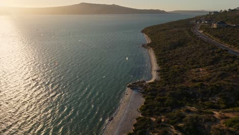 Bahía-De-Tiburones-Durante-Un-Día-Ventoso-Con-Kitesurfistas,-Cerca-De-La-Puesta-De-Sol,-Tiro-Aéreo