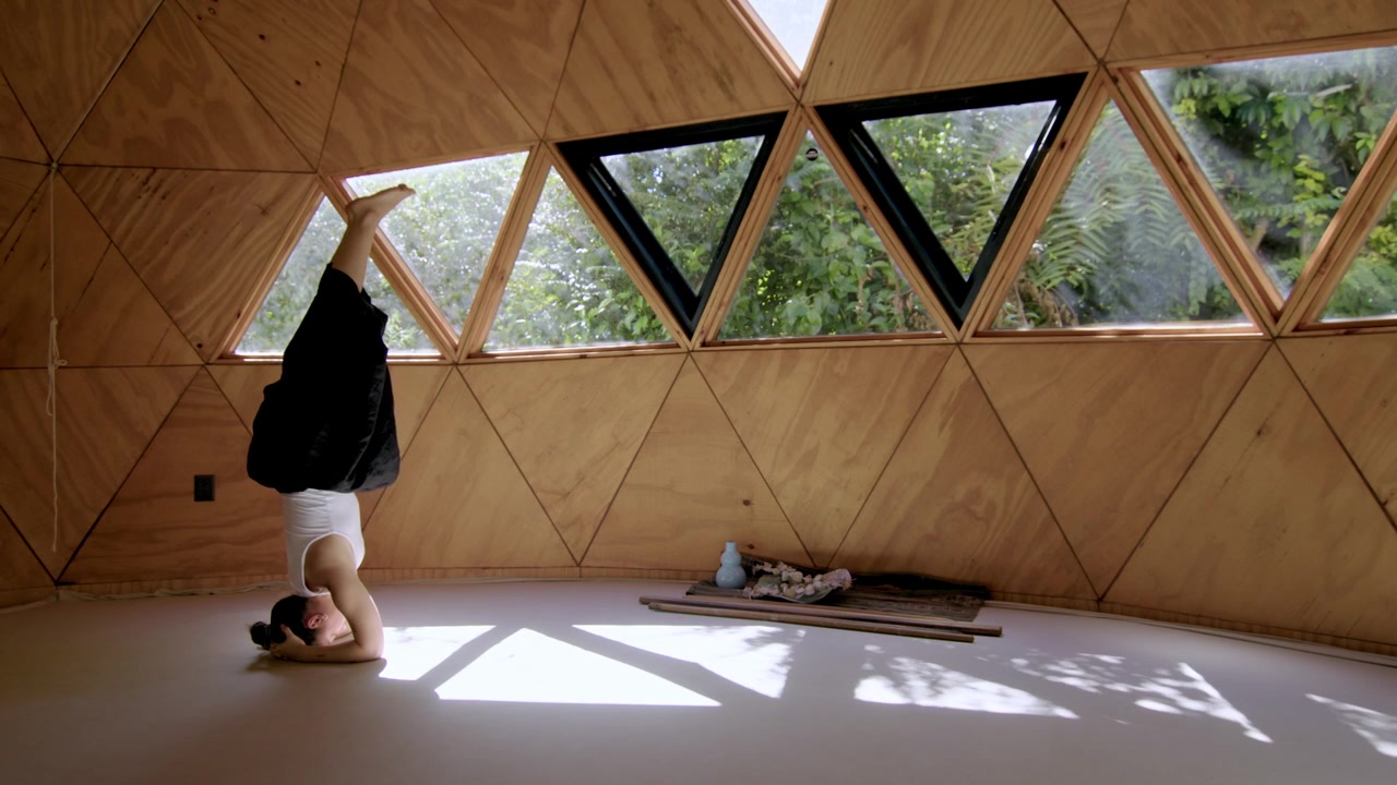 Uma sessão de yoga serena terminando com a postura do cachorro olhando para baixo e invertida sobre a cabeça, com uma mulher hispânica em um estúdio zen geométrico, praticando posturas relaxantes em um espaço ao ar livre.