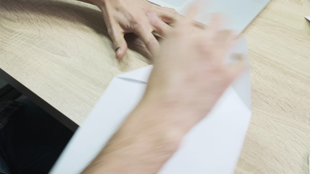Person folding a paper airplane at a desk