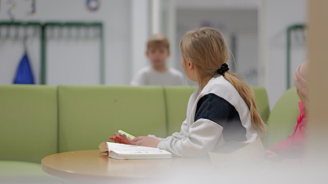 boy talks across the room to young girl studying and she gets frustrated