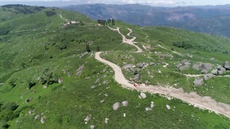 Off-road-red-rally-car-in-dirt-terrain-speeding-down-a-mountain