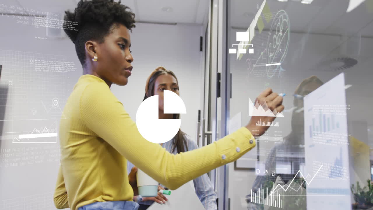 Analyzing data charts on transparent board, businesswomen in modern office