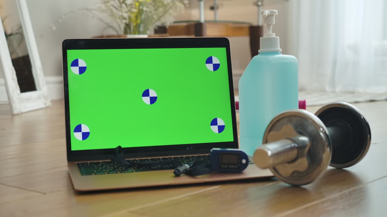 pantalla verde en el portátil, manivela, oxímetro de pulso y botella de desinfectante en el interior. monitor chromakey con equipos de atención médica en el hogar. concepto de deporte y pandemia de covid. cine 4k prores hq.