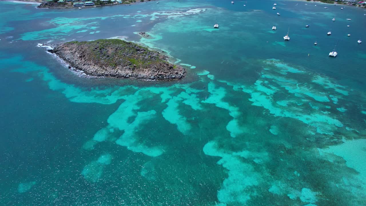 Aerial over shallow clear blue waters from Pinel Island to St