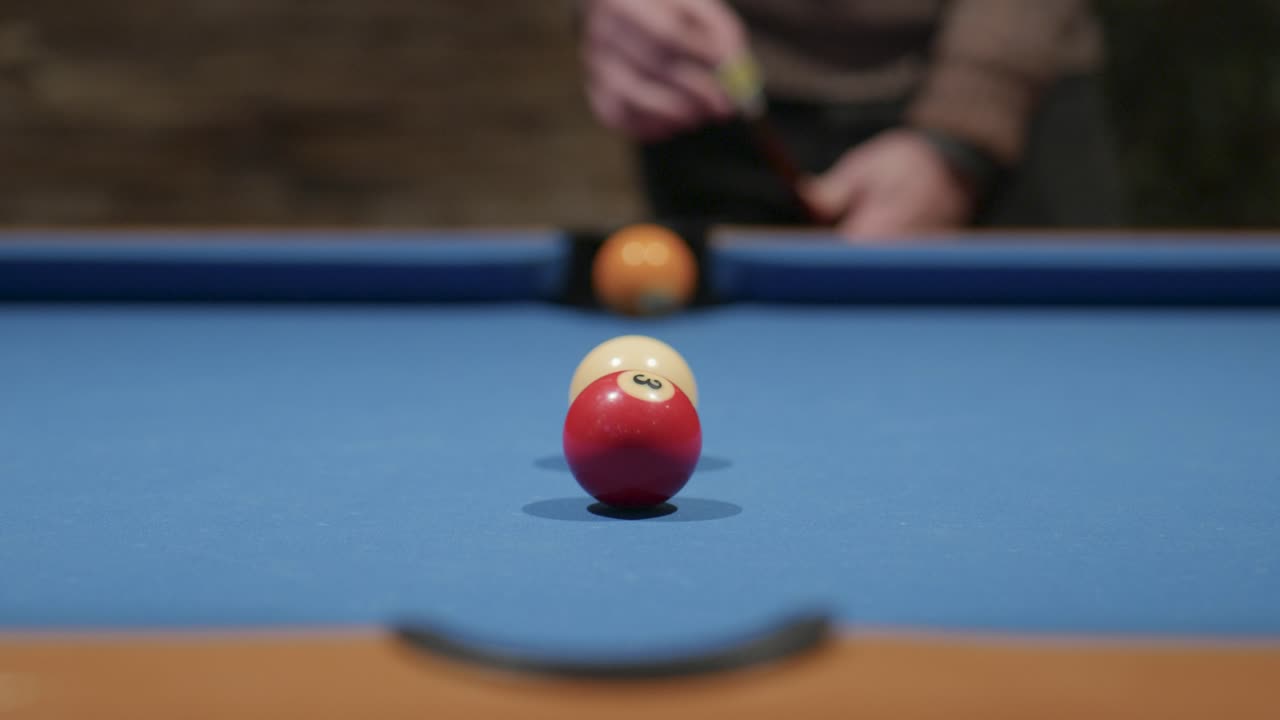 A man chalks his cue and then pots a red ball