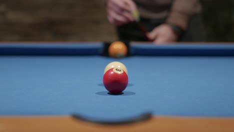 a man chalks his cue and then pots a red ball