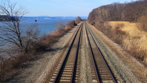 Luftaufnahmen-Von-Drohnen-Auf-Eisenbahnschienen-In-Einem-Flusstal-Mit-Wasser-Im-Frühjahr