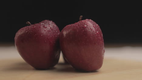 manzana fresca de 4 k en una mesa girando a su alrededor con luz cálida y fondo negro en un ambiente oscuro interior con accesorios simples dispuestos uno al lado del otro