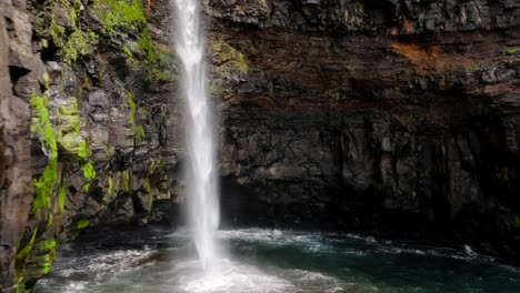 una impresionante cascada vertical se sumerge en el océano en medio de acantilados rocosos en las islas feroe