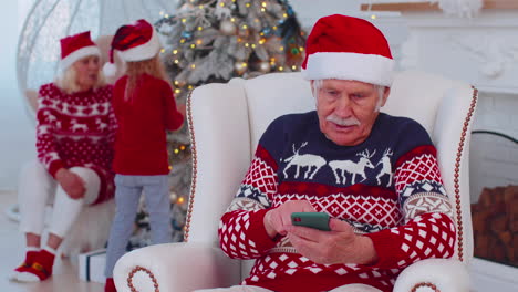 Senior-old-grandfather-man-buy-Christmas-gift-presents-doing-online-shopping-on-mobile-phone-at-home