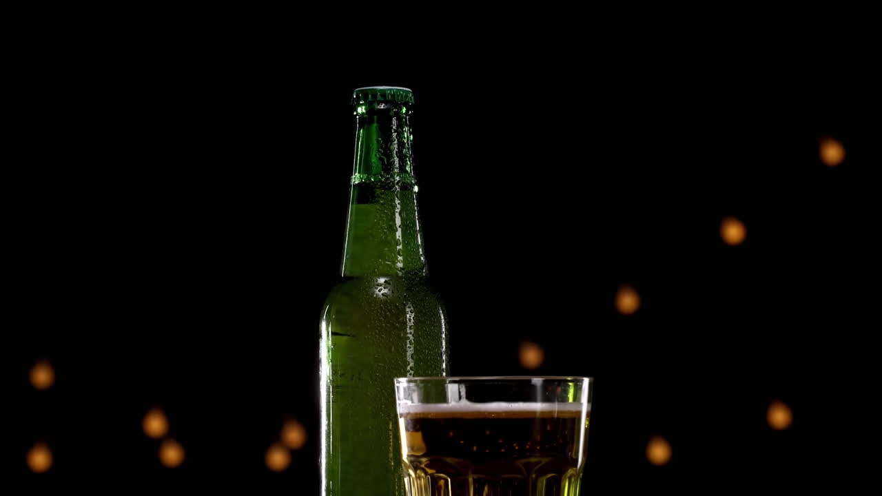 Primo piano di una bottiglia di birra di frumento o lager in vetro verde, fredda e refrigerata, con goccioline di condensa che coprono la superficie del contenitore, evidenziando la sua qualità rinfrescante e frizzante, isolata su sfondo nero