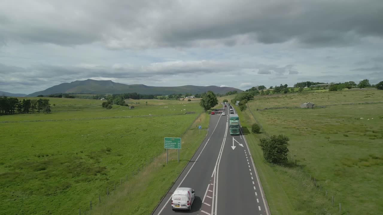 바쁜 시골 고속도로 a66 자동차와 트럭과 구름진 여름 날 지평선에 산 blencathra