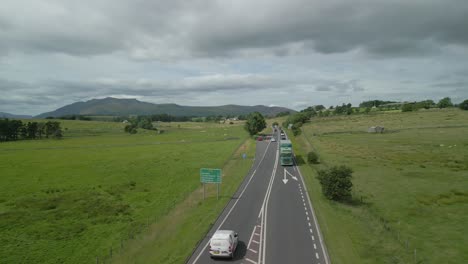 Busy-countryside-highway-A66-with-cars-and-trucks-and-mountain-Blencathra-on-horizon-on-cloudy-summer-day