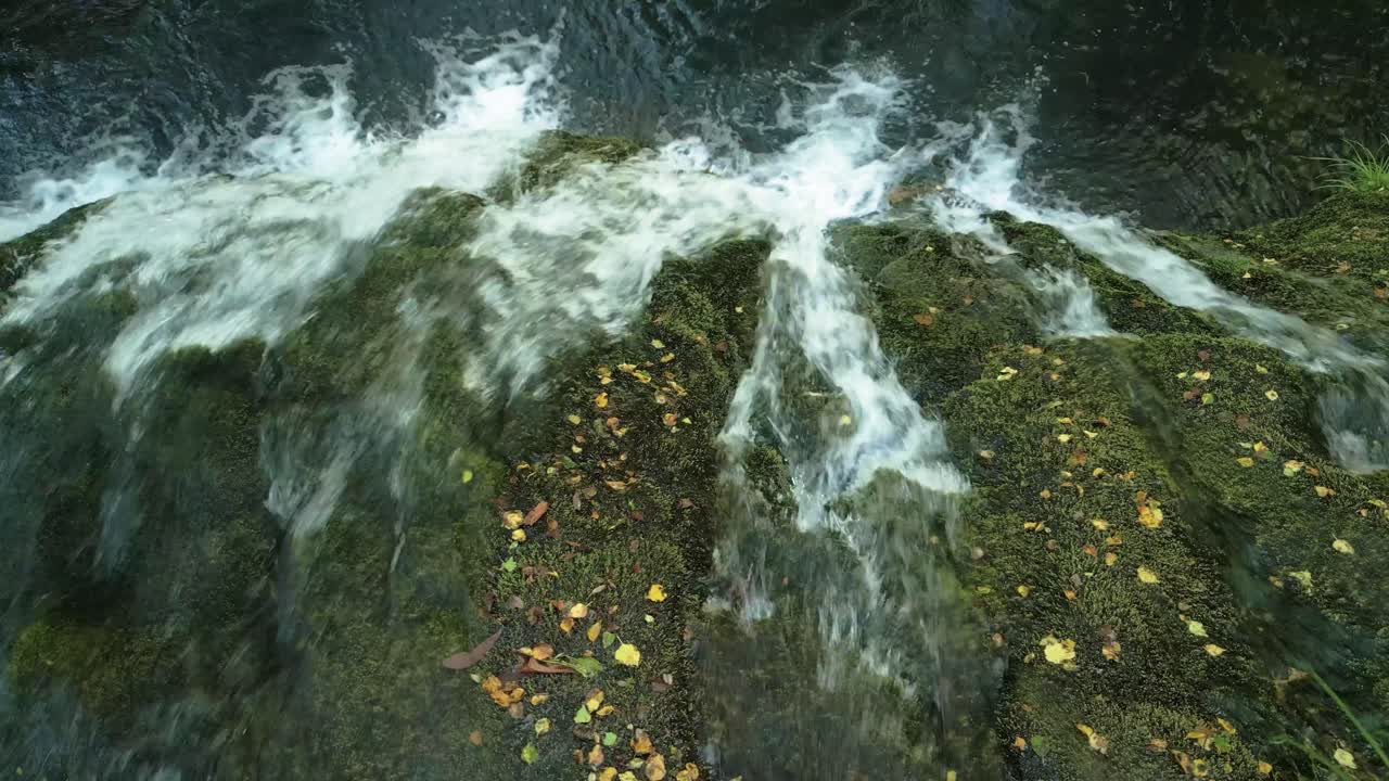 vista panorámica de la cascada en las rocas con musgo verde en el bosque