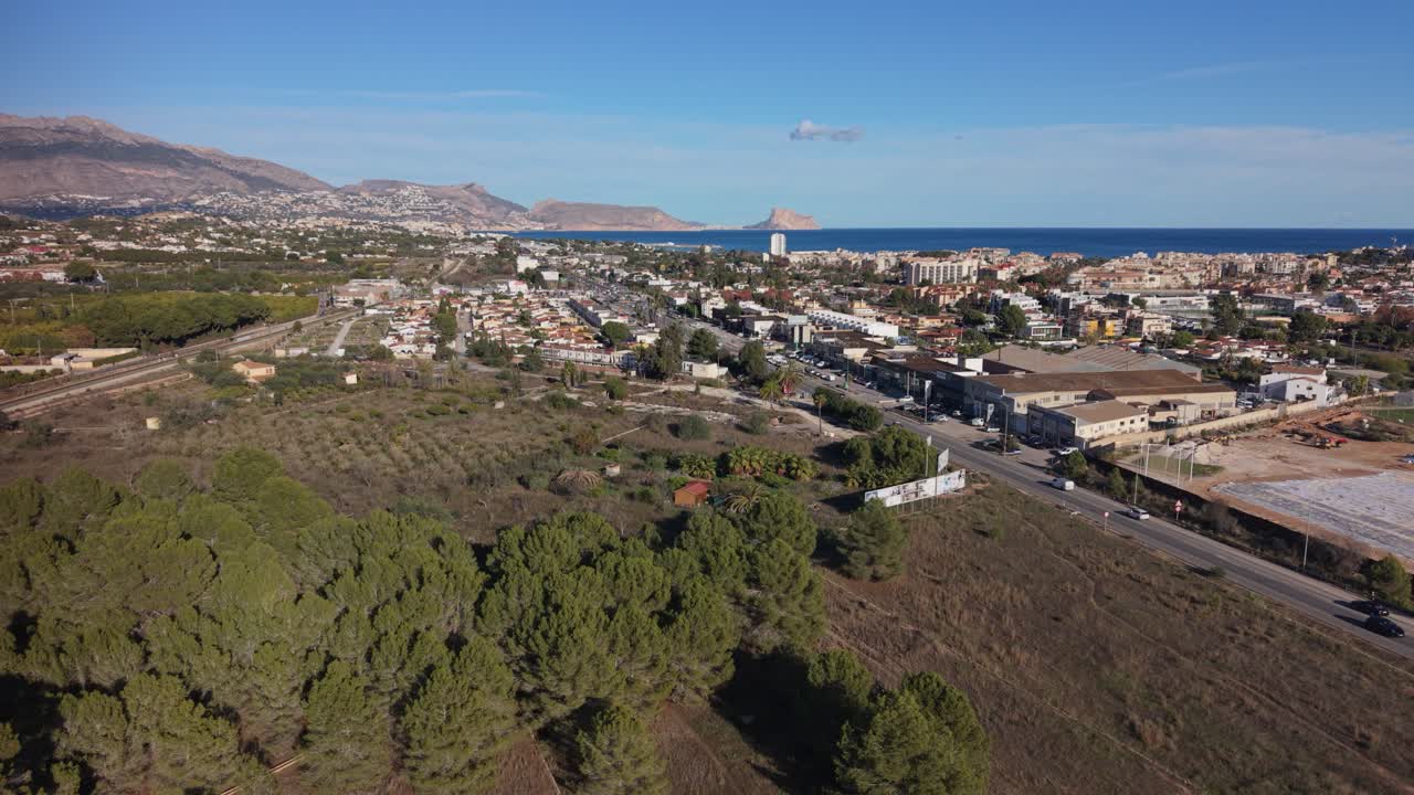 Albir, Costa Blanca, Spagna. Veduta aerea statica della strada principale per Albir con la campagna spagnola, viste lontane del mare, Benidorm e delle montagne sotto un sole splendente con cielo azzurro limpido.