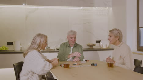 three happy senior friends playing poker at home 1