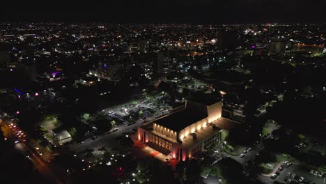 teatro nacional eduardo brito iluminado por la noche y la ciudad de santo domingo en el fondo, república dominicana