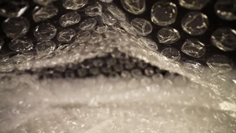 pulling out of a bubble wrap bag, top of the bag flutters slightly, focused on the top third of the bag