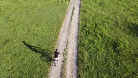 Imágenes-Aéreas-De-Un-Hombre-Montando-Su-Bicicleta-En-Una-Carretera-Rural-En-Un-Día-Soleado-De-Verano