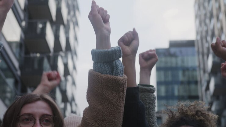 vista de cerca de activistas levantando puños durante una protesta contra el cambio climático en la calle