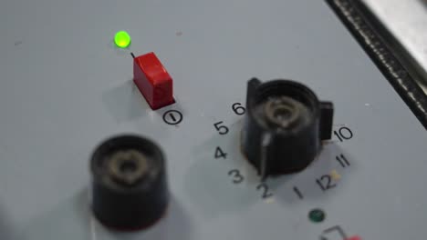 A close-up of a railway control panel with illuminated lights, buttons, and numbered dials used for train operations