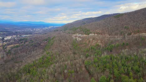 A-drone-panning-sideways-over-a-mountain-valley-near-sunset-in-late-fall-with-mountains-in-the-distance-and-farmland-below