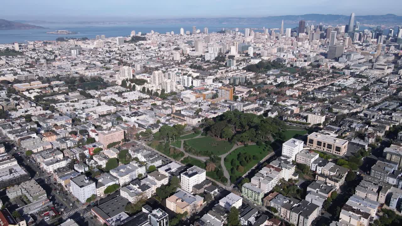 샌프란시스코의 알라모 스어 파크 (alamo square park) 의 공중 풍경, 울창한 초록색과 빅토리아 시대의 상징적인 집들을 보여준다.