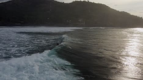 Surfista-Monta-Una-Ola-De-Surf-Grande-Y-Agresiva-En-La-Orilla-Con-Una-Iluminación-Dorada-Del-Atardecer