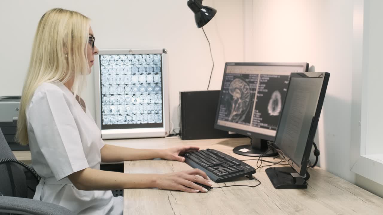 una radióloga profesional examina los resultados de una tomografía computarizada o una resonancia magnética cerebral, trabajando en una pantalla de computadora en su escritorio personal en el hospital