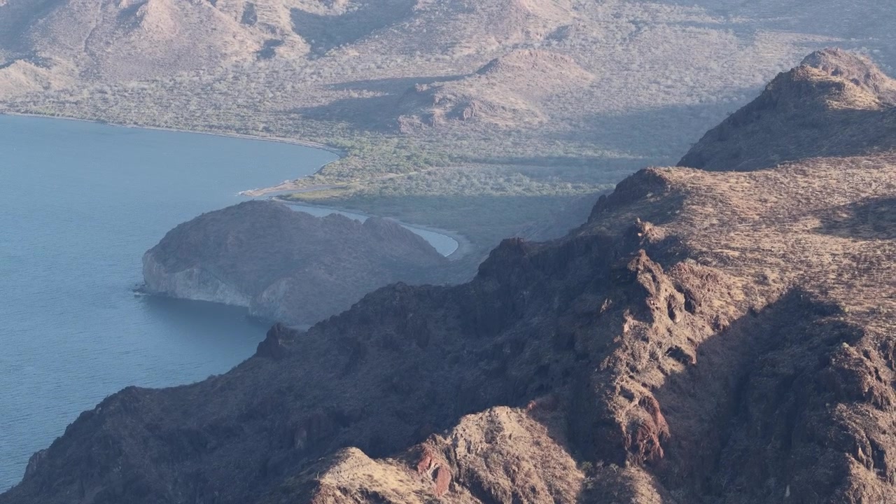 Crinali stratificati che sfumano nella foschia del crepuscolo sopra il mare vicino a La Paz, Messico.