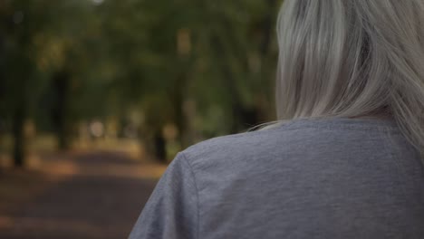 mujer caminando por el parque en otoño por encima del hombro plano medio