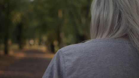 woman walking through park in autumn over the shoulder medium shot